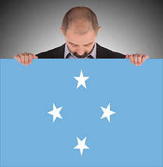 Image showing Smiling businessman holding a big card or flag