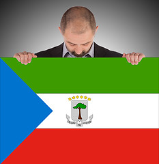 Image showing Smiling businessman holding a big card or flag