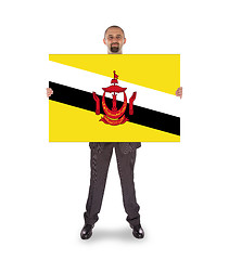 Image showing Smiling businessman holding a big card or flag