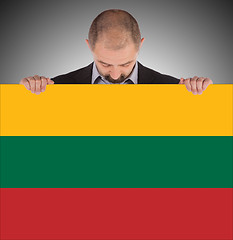 Image showing Smiling businessman holding a big card or flag