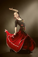 Image showing young woman dancing flamenco on black