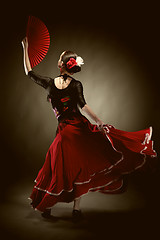 Image showing young woman dancing flamenco on black