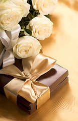 Image showing Bouquet of beautiful roses next to a gift