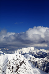 Image showing Winter snowy sunlit mountains and sky with clouds
