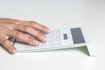 Image showing Hand typing on calculator