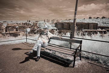 Image showing Man on bench with city in background