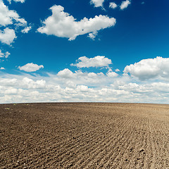Image showing plowed field and deep blue sky with clouds over it