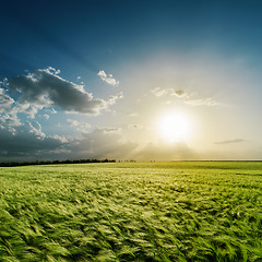 Image showing cloudy sunset over green field