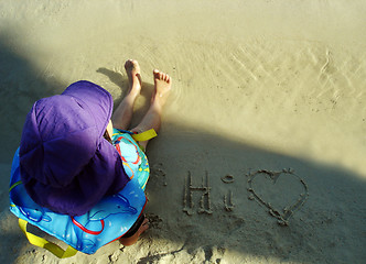 Image showing Young child sitting on the sand at the beach