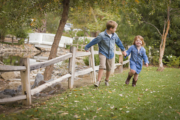 Image showing Happy Young Brother and Sister Running Outside