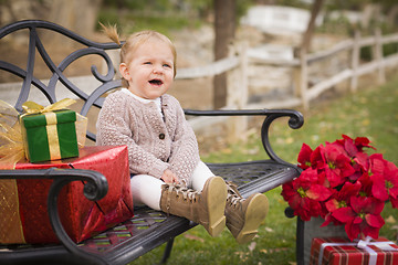Image showing Young Toddler Child Sitting on Bench with Christmas Gifts Outsid