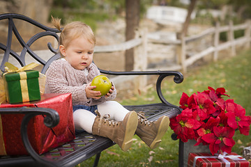 Image showing Young Toddler Child Sitting on Bench with Christmas Gifts Outsid