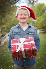 Image showing Young Boy Wearing Holiday Clothing Holding Christmas Gift Outsid