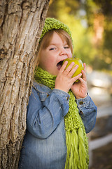 Image showing Young Girl Wearing Green Scarf and Hat Eating Apple Outside