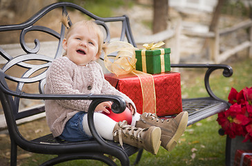 Image showing Young Toddler Child Sitting on Bench with Christmas Gifts Outsid