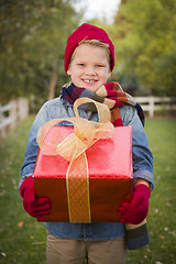 Image showing Young Boy Wearing Holiday Clothing Holding Christmas Gift Outsid