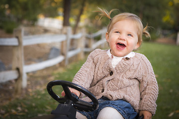 Image showing Young Toddler Laughing and Playing on Toy Tractor Outside