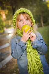 Image showing Young Girl Wearing Green Scarf and Hat Eating Apple Outside