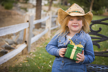 Image showing Young Girl Wearing Holiday Clothing Holding Christmas Gift Outsi