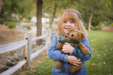 Image showing Cute Smiling Young Girl Hugging Her Teddy Bear Outside