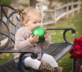 Image showing Toddler Child Sitting on Bench with Christmas Ornament Outside