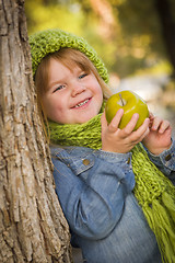 Image showing Young Girl Wearing Green Scarf and Hat Eating Apple Outside