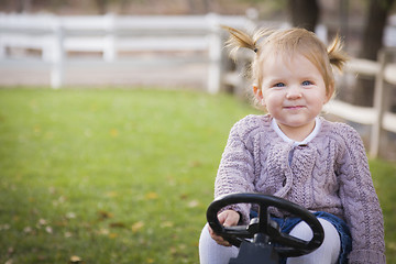 Image showing Young Toddler Smiling and Playing on Toy Tractor Outside