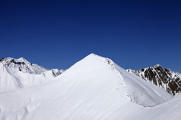 Image showing Snowy off-piste slope and blue clear sky at nice winter day