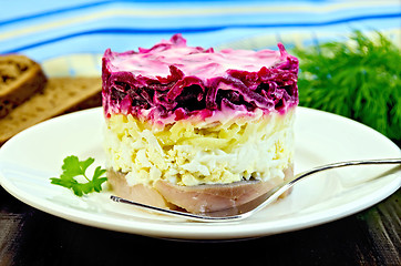 Image showing Herring with vegetables in white plate with a fork on the board