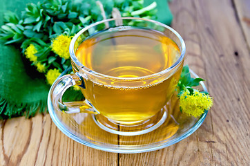 Image showing Herbal tea in a cup with a bouquet of Rhodiola rosea on the boar