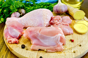 Image showing Chicken leg cut on a wooden board with ginger