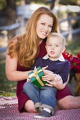 Image showing Young Boy Holding Christmas Gift with His Mom in Park