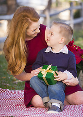 Image showing Young Boy Holding Christmas Gift with His Mom in Park