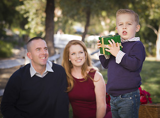 Image showing Young Boy Holding Christmas Gift in Park While Parents Look