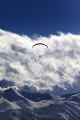 Image showing Winter mountains with clouds and silhouette of parachutist