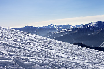 Image showing Ski slope with trace of ski, snowboards and mountains in haze