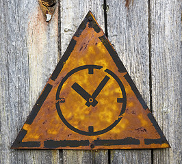 Image showing Icon of Clock Face on Rusty Warning Sign.