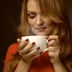 Image showing woman holding hot cup and smiles