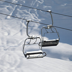 Image showing Two chair-lift with snowdrift in sun morning. Close-up view.