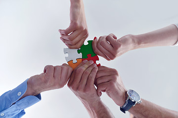 Image showing Group of business people assembling jigsaw puzzle