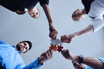 Image showing Group of business people assembling jigsaw puzzle