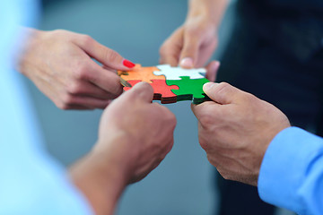 Image showing Group of business people assembling jigsaw puzzle