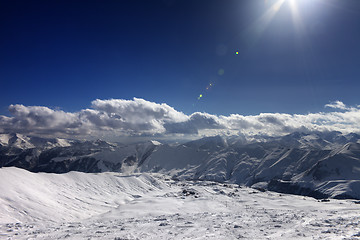 Image showing Ski slope and blue sky with sun rays