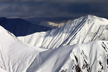 Image showing Snowy sunlit mountains and overcast sky