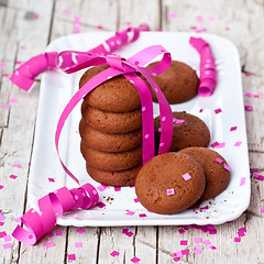 Image showing plate of fresh chocolate cookies with pink ribbon and confetti 