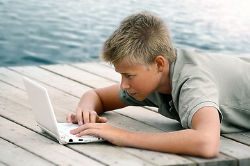 Image showing Boy writing with computer at the sea