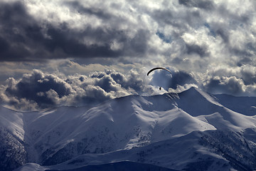 Image showing Evening mountain with clouds and silhouette of parachutist