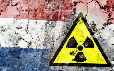 Image showing Old cracked wall with radiation warning sign and painted flag