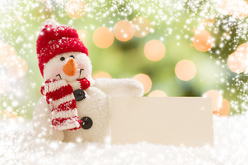 Image showing Snowman with Blank White Card Over Abstract Snow and LIght