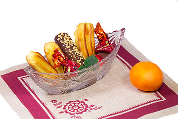 Image showing Cakes and sweets in a crystal vase, a tangerine, a napkin on a w